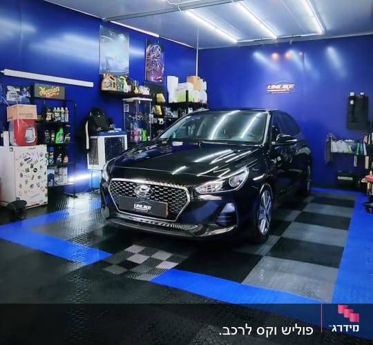 רכב שחור בחדר דיטיילינג עם ציוד ניקוי